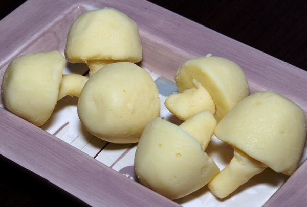 4 white chocolate ganache shaped like mushrooms in a white plate