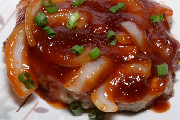 A plate containing a Chinese Style Pork Chop covered in a Sweet Onion Sauce
