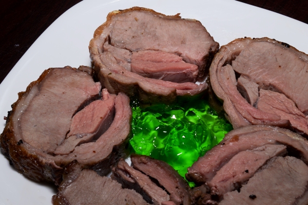 slices of a boneless lamb loin on a plate with mint sauce